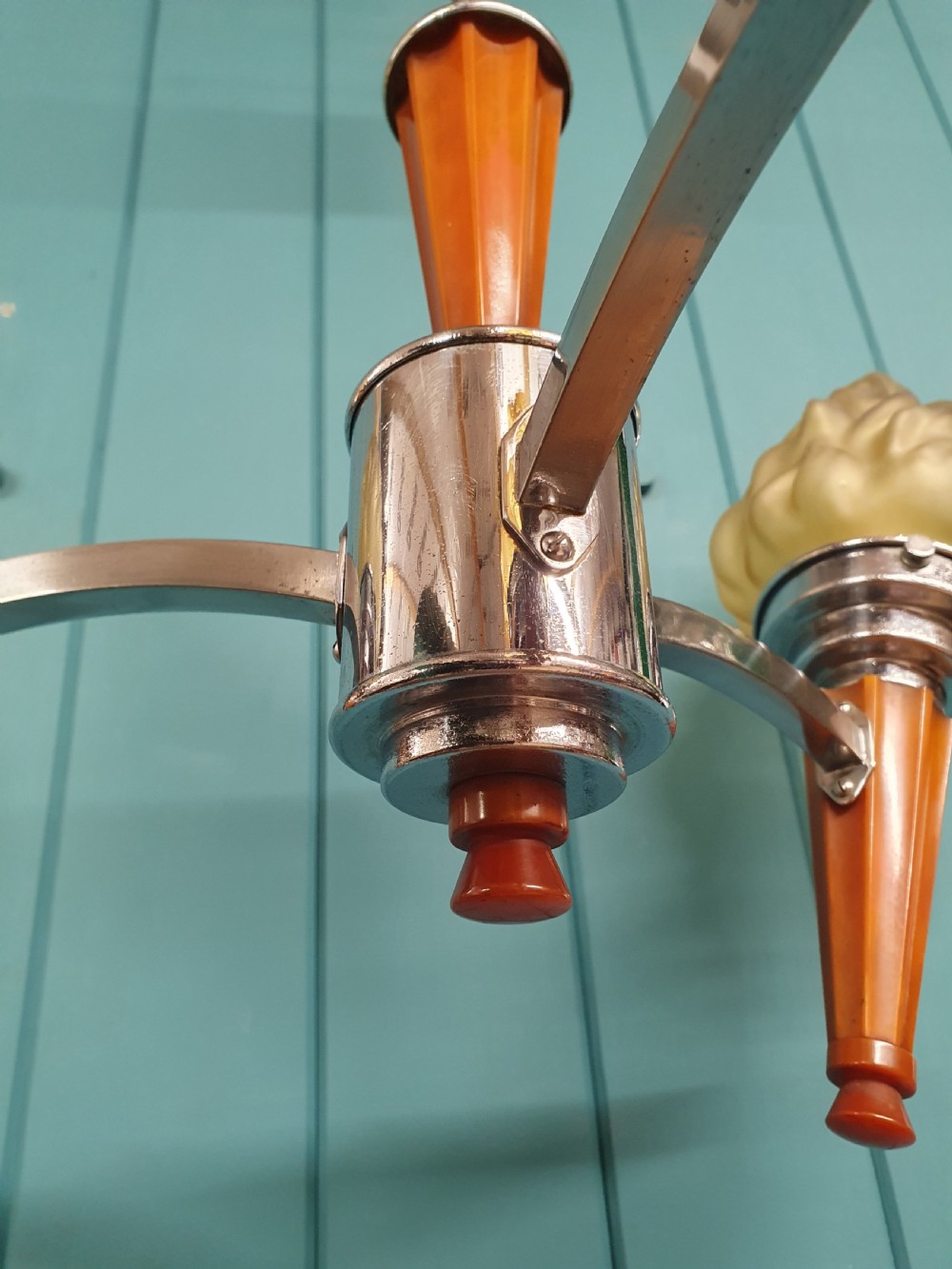 An Art Deco three-light chandelier featuring chrome stems, orange torch holders, and flame-shaped frosted glass shades. View VII