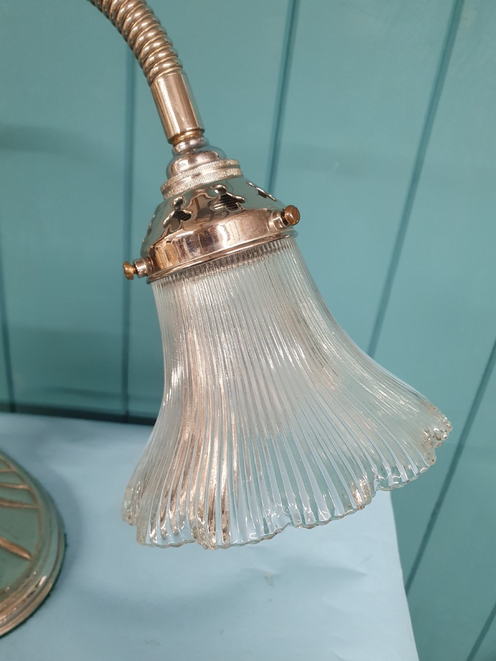 An Art Deco brass desk lamp featuring a shell-shaped base, flexible gooseneck arm, and a fluted clear glass shade. View VII
