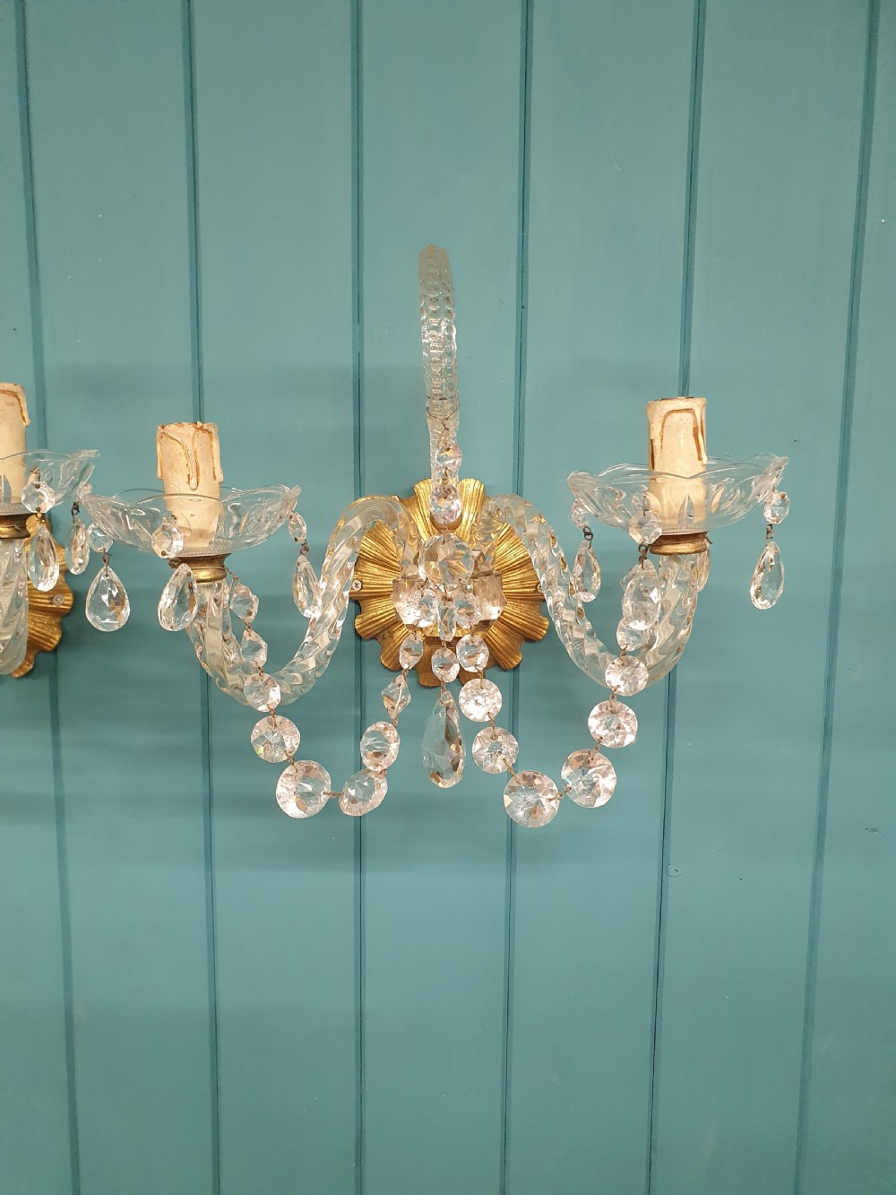 A pair of early 20th-century French double-arm glass wall sconces with crystal droplets, gilt brass backplates, and black lampshades. View VI