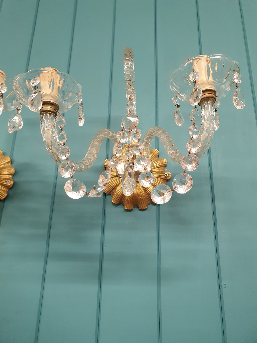 A pair of early 20th-century French double-arm glass wall sconces with crystal droplets, gilt brass backplates, and black lampshades. View IX