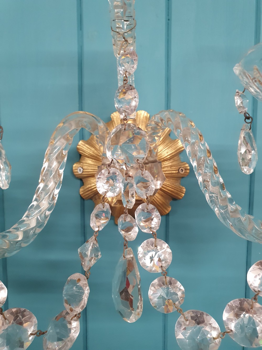 A pair of early 20th-century French double-arm glass wall sconces with crystal droplets, gilt brass backplates, and black lampshades. View X