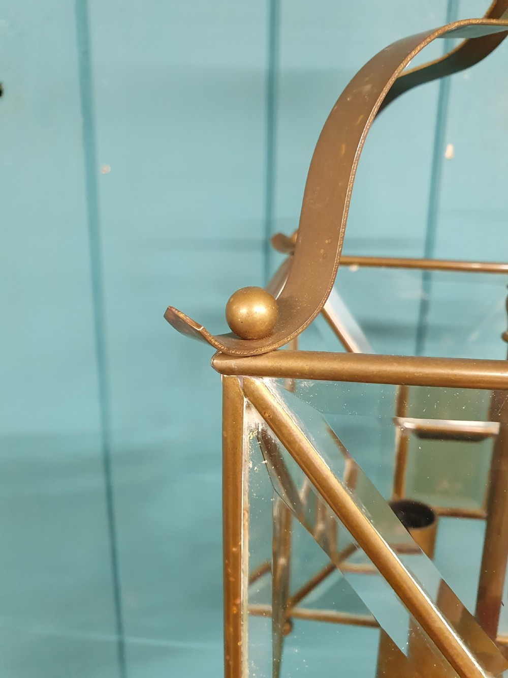A square brass Arts and Crafts hall lantern featuring geometric bevelled glass panels suspended from a brass chain. View VII