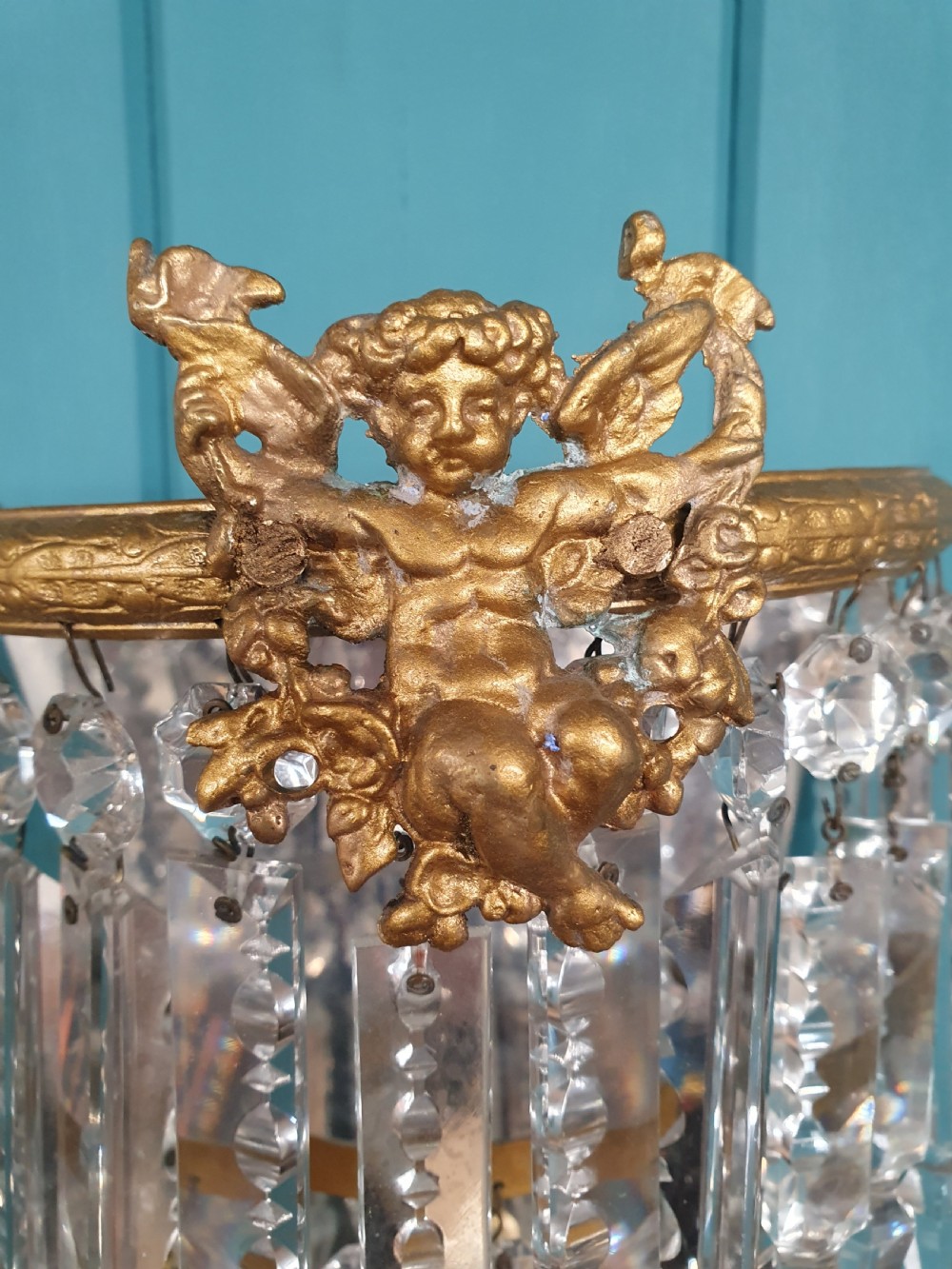 A pair of early 20th-century gilded brass wall sconces featuring top cherub figures and tiered hanging crystal prisms. View III