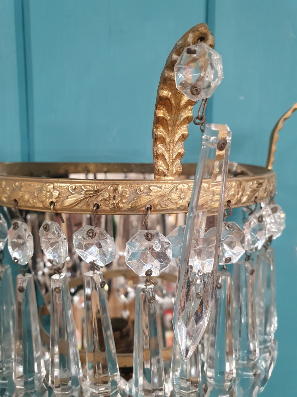 A pair of antique gilt brass wall lights featuring tiered crystal prisms, decorative top spikes, and mirrored backings. View II
