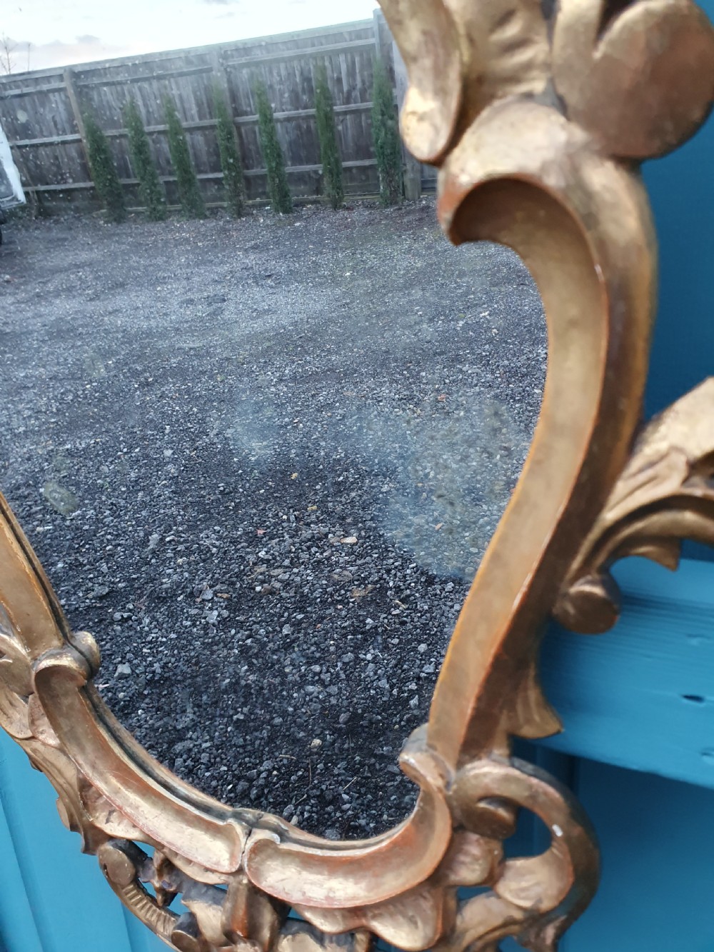 A matching pair of carved Italian Rococo style giltwood wall mirrors featuring leaf crests and elaborate floral scrollwork. View II