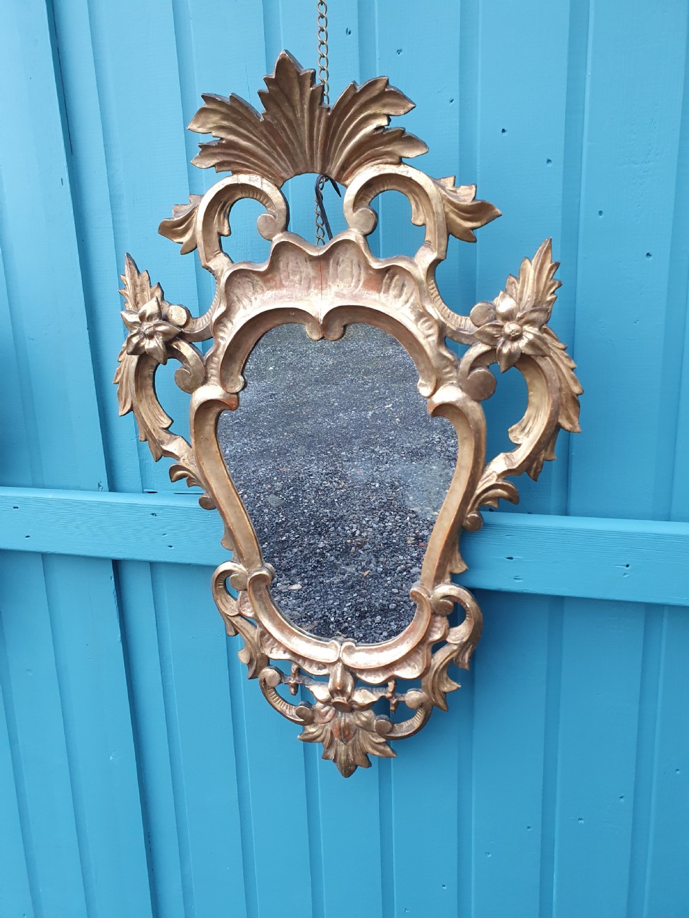 A matching pair of carved Italian Rococo style giltwood wall mirrors featuring leaf crests and elaborate floral scrollwork. View IV