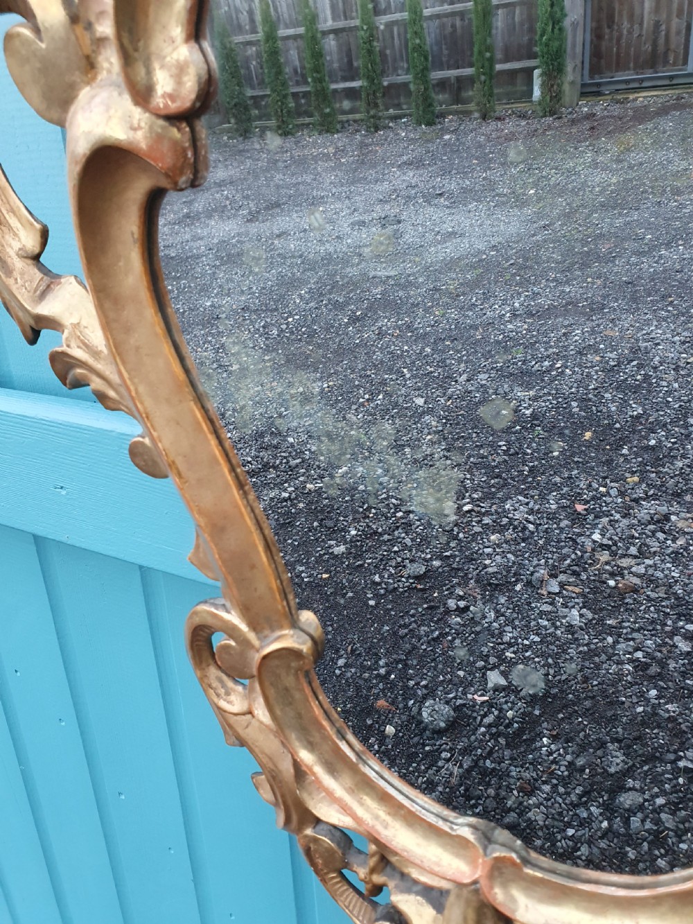A matching pair of carved Italian Rococo style giltwood wall mirrors featuring leaf crests and elaborate floral scrollwork. View X