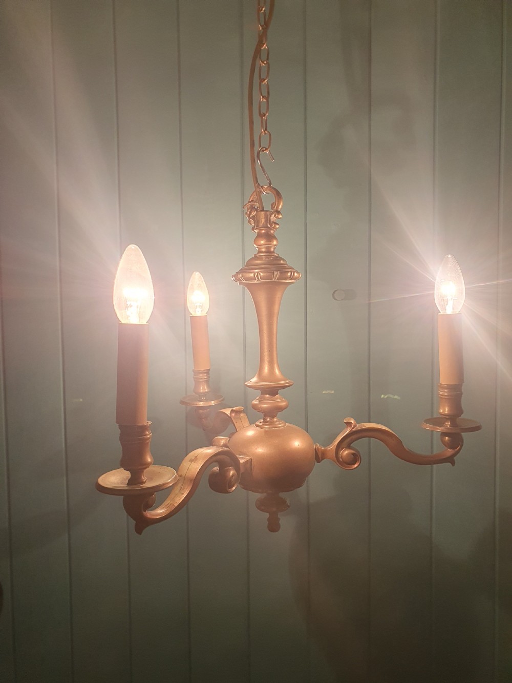 A three-arm Dutch Flemish style brass chandelier featuring a central turned baluster stem and s-scroll arms supporting faux candle sockets. View III