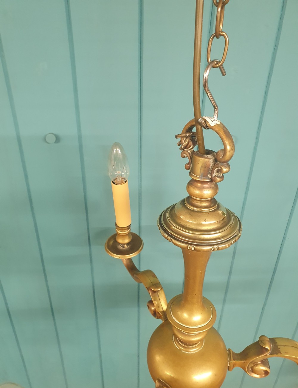A three-arm Dutch Flemish style brass chandelier featuring a central turned baluster stem and s-scroll arms supporting faux candle sockets. View IV