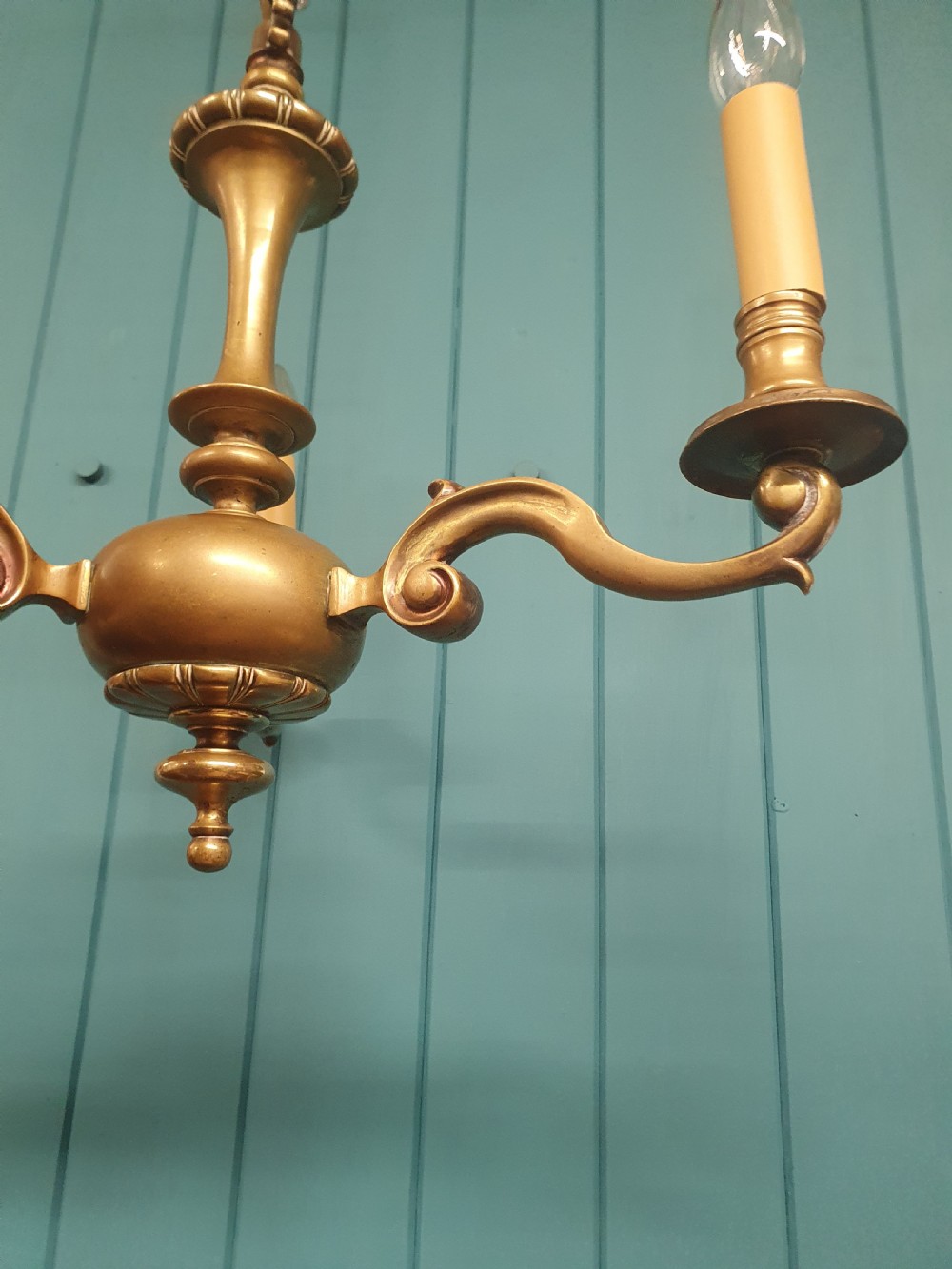 A three-arm Dutch Flemish style brass chandelier featuring a central turned baluster stem and s-scroll arms supporting faux candle sockets. View VII