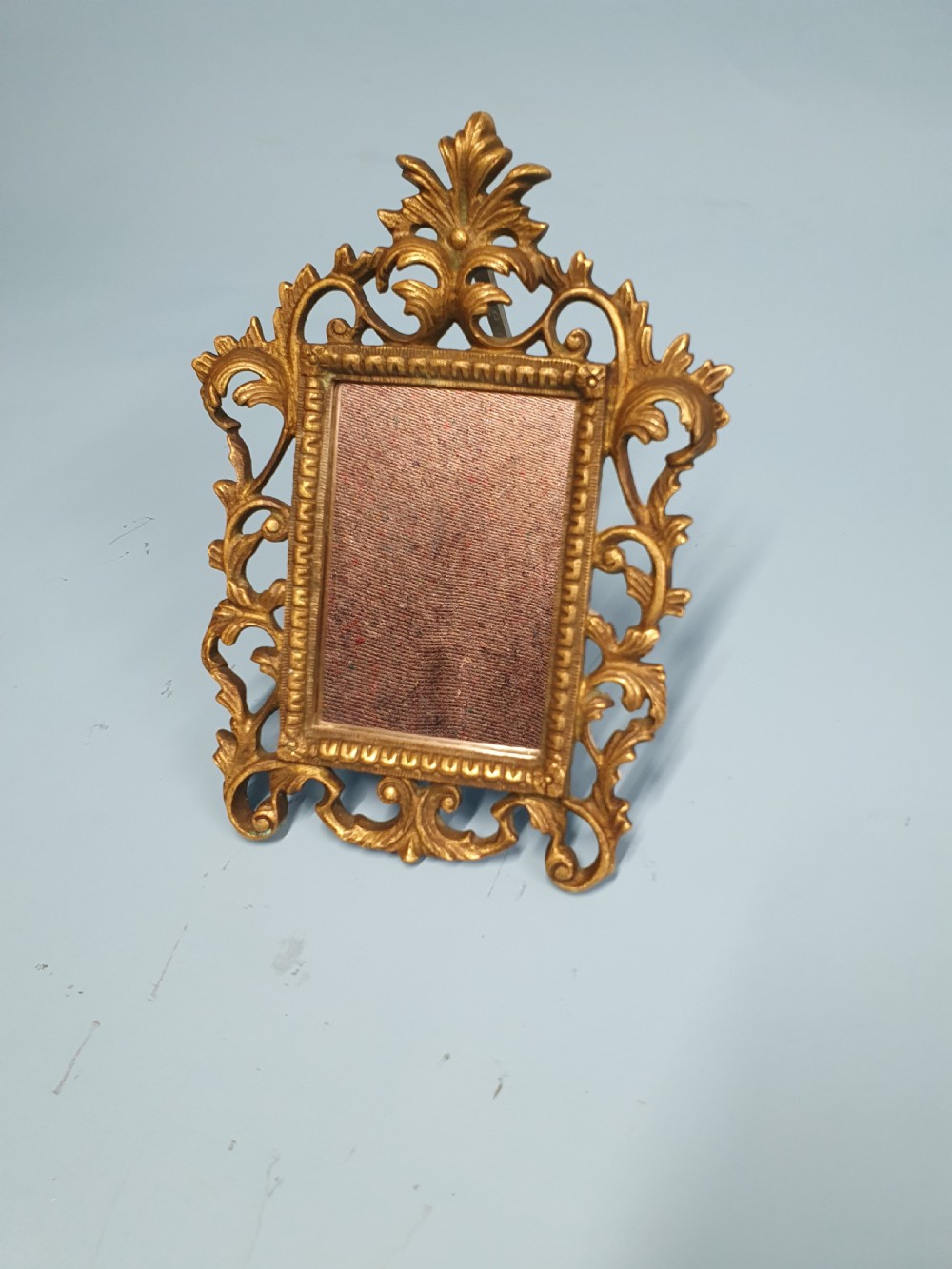 An ornate late 19th-century cast brass table mirror featuring pierced scrollwork frame and an acanthus leaf crest.