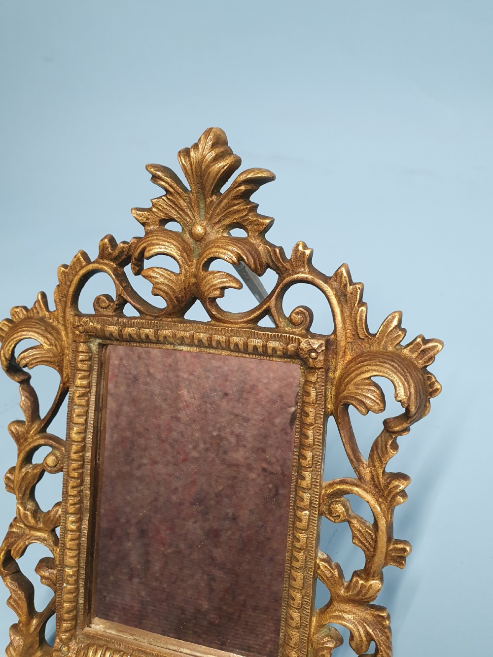 An ornate late 19th-century cast brass table mirror featuring pierced scrollwork frame and an acanthus leaf crest. View V