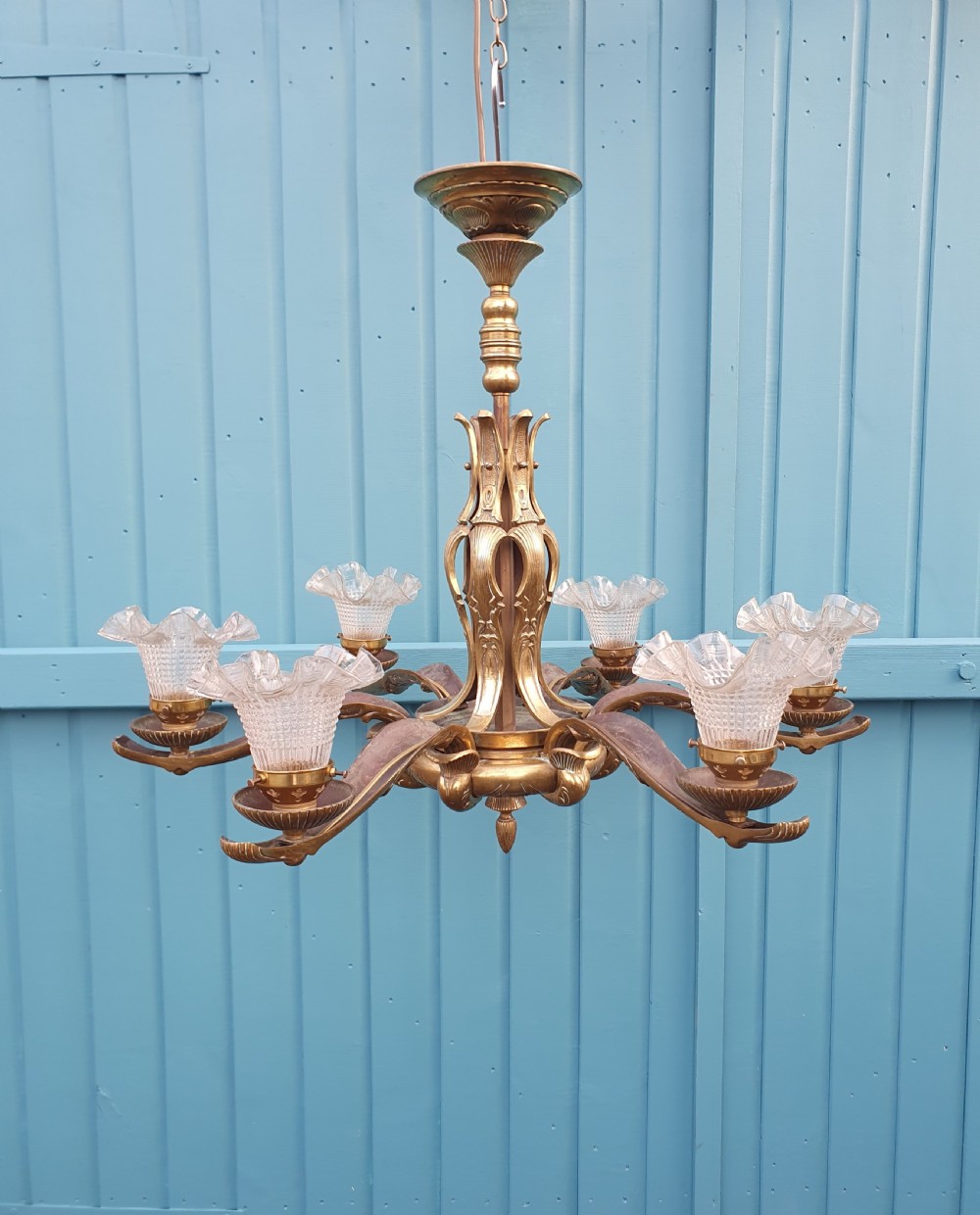 An early 20th-century six-arm brass ceiling chandelier featuring frilled clear glass shades and a central cast brass stem.