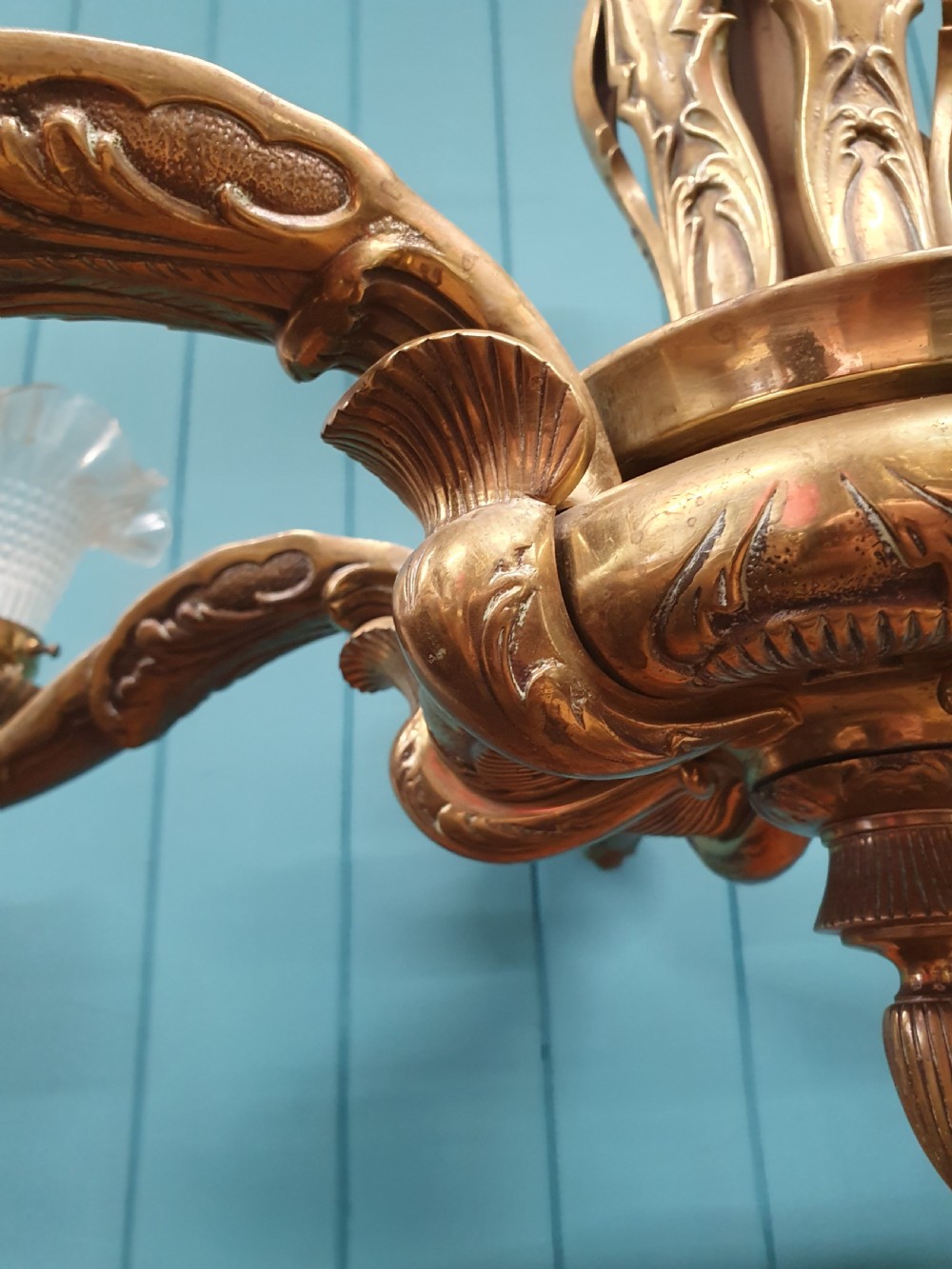 An early 20th-century six-arm brass ceiling chandelier featuring frilled clear glass shades and a central cast brass stem. View II