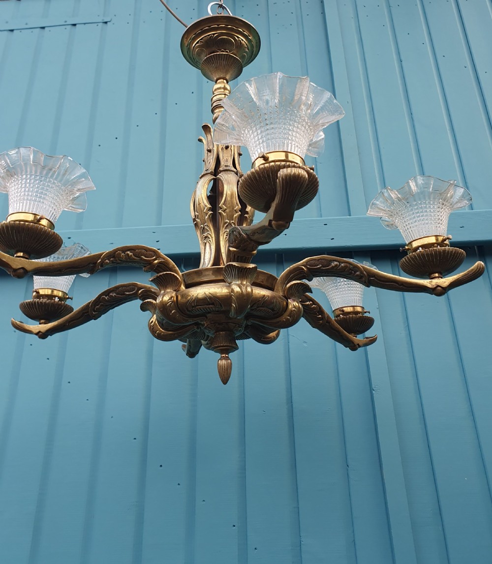 An early 20th-century six-arm brass ceiling chandelier featuring frilled clear glass shades and a central cast brass stem. View IV