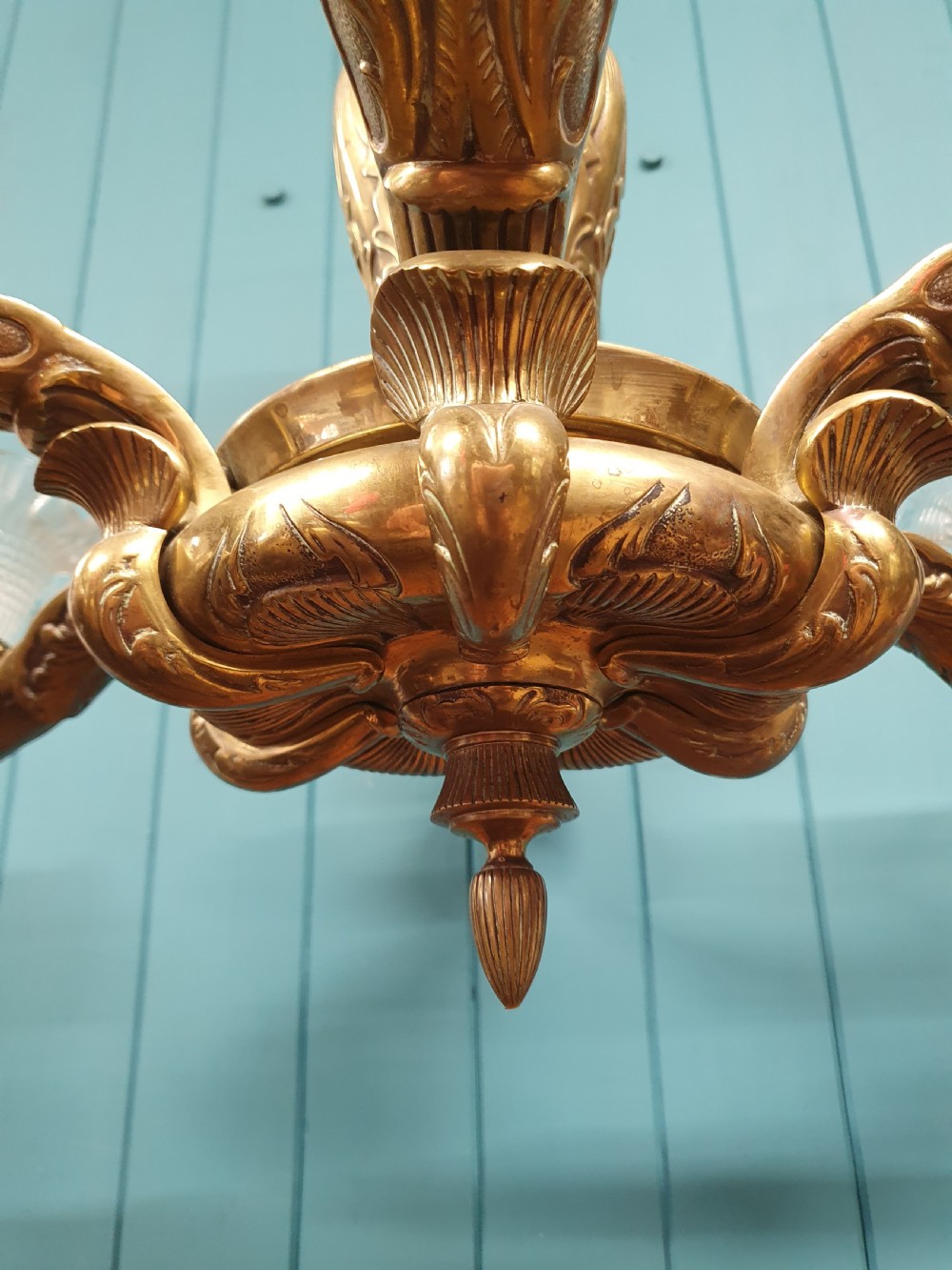 An early 20th-century six-arm brass ceiling chandelier featuring frilled clear glass shades and a central cast brass stem. View V