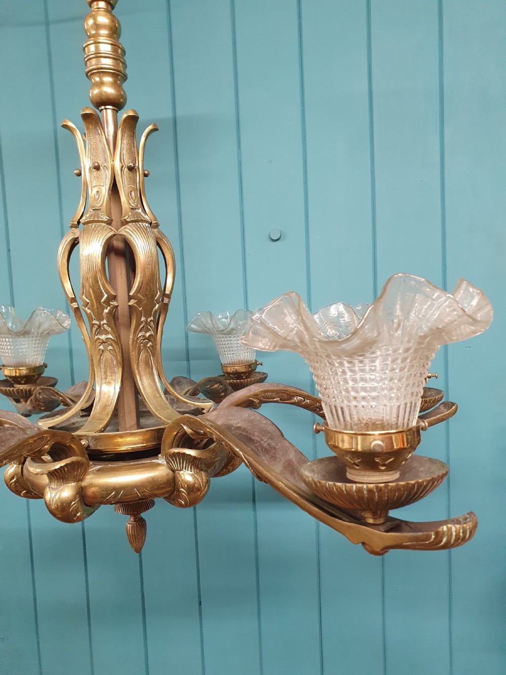 An early 20th-century six-arm brass ceiling chandelier featuring frilled clear glass shades and a central cast brass stem. View VI