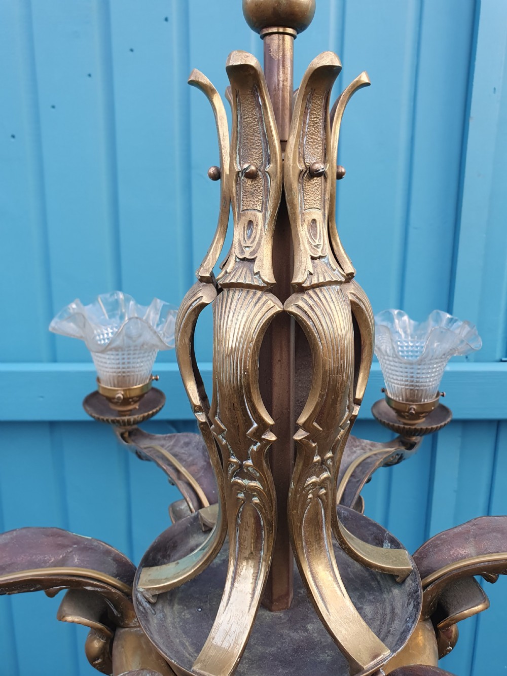 An early 20th-century six-arm brass ceiling chandelier featuring frilled clear glass shades and a central cast brass stem. View VII