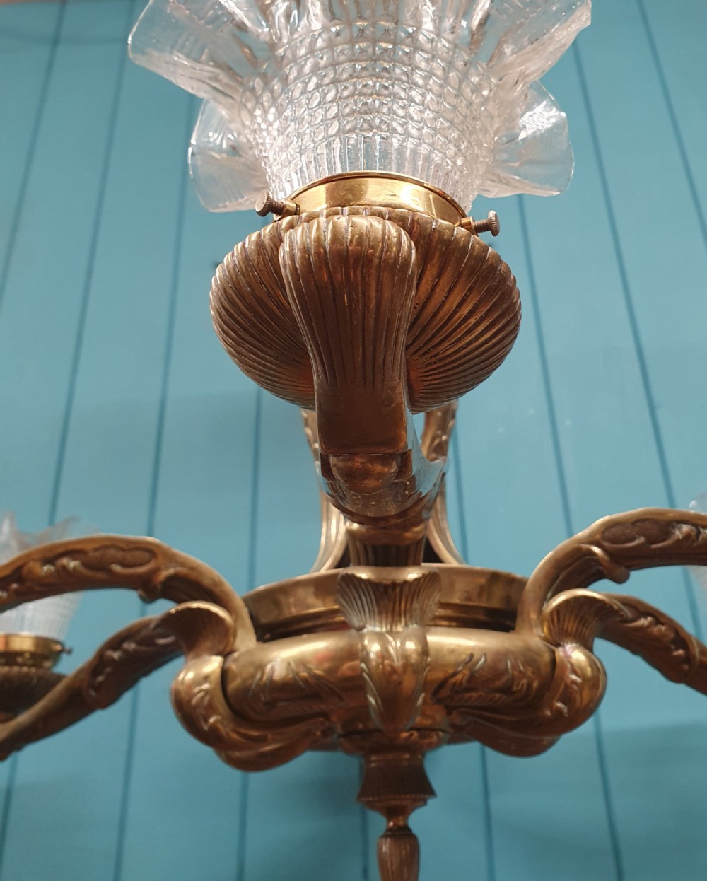 An early 20th-century six-arm brass ceiling chandelier featuring frilled clear glass shades and a central cast brass stem. View VIII