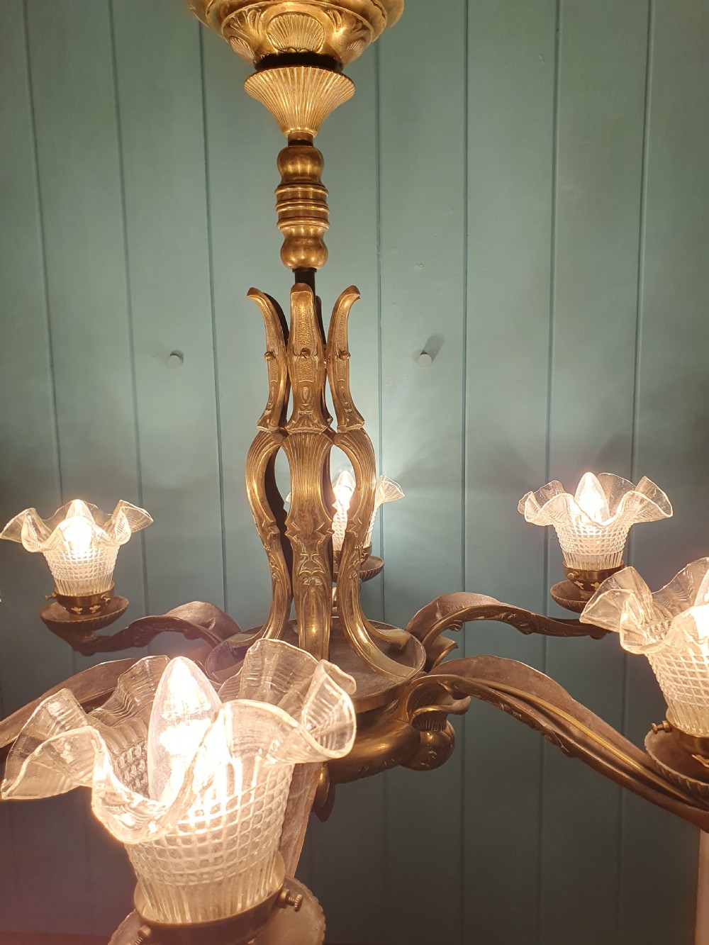 An early 20th-century six-arm brass ceiling chandelier featuring frilled clear glass shades and a central cast brass stem. View IX