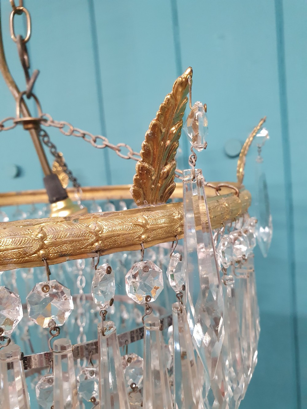 An early 20th-century chandelier with concentric tiers of clear crystal glass spikes suspended from a decorative gilt brass rim. View III