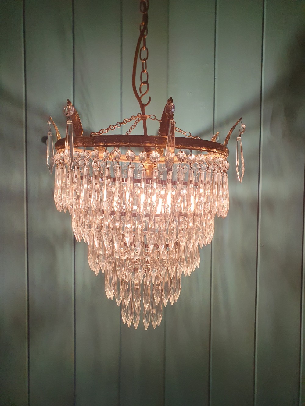 An early 20th-century chandelier with concentric tiers of clear crystal glass spikes suspended from a decorative gilt brass rim. View IV