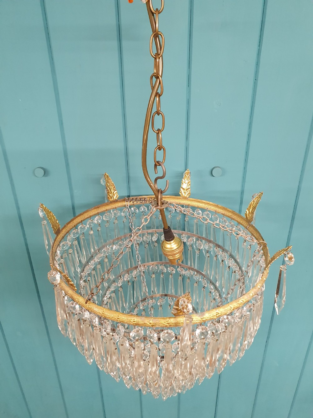 An early 20th-century chandelier with concentric tiers of clear crystal glass spikes suspended from a decorative gilt brass rim. View VI