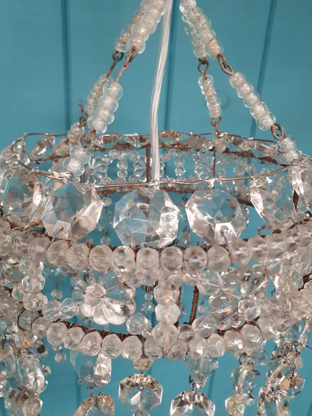 A small cylindrical ceiling light shade constructed from clear glass beads on a wire frame, featuring floral pattern bands and cascading faceted bead strands. View III