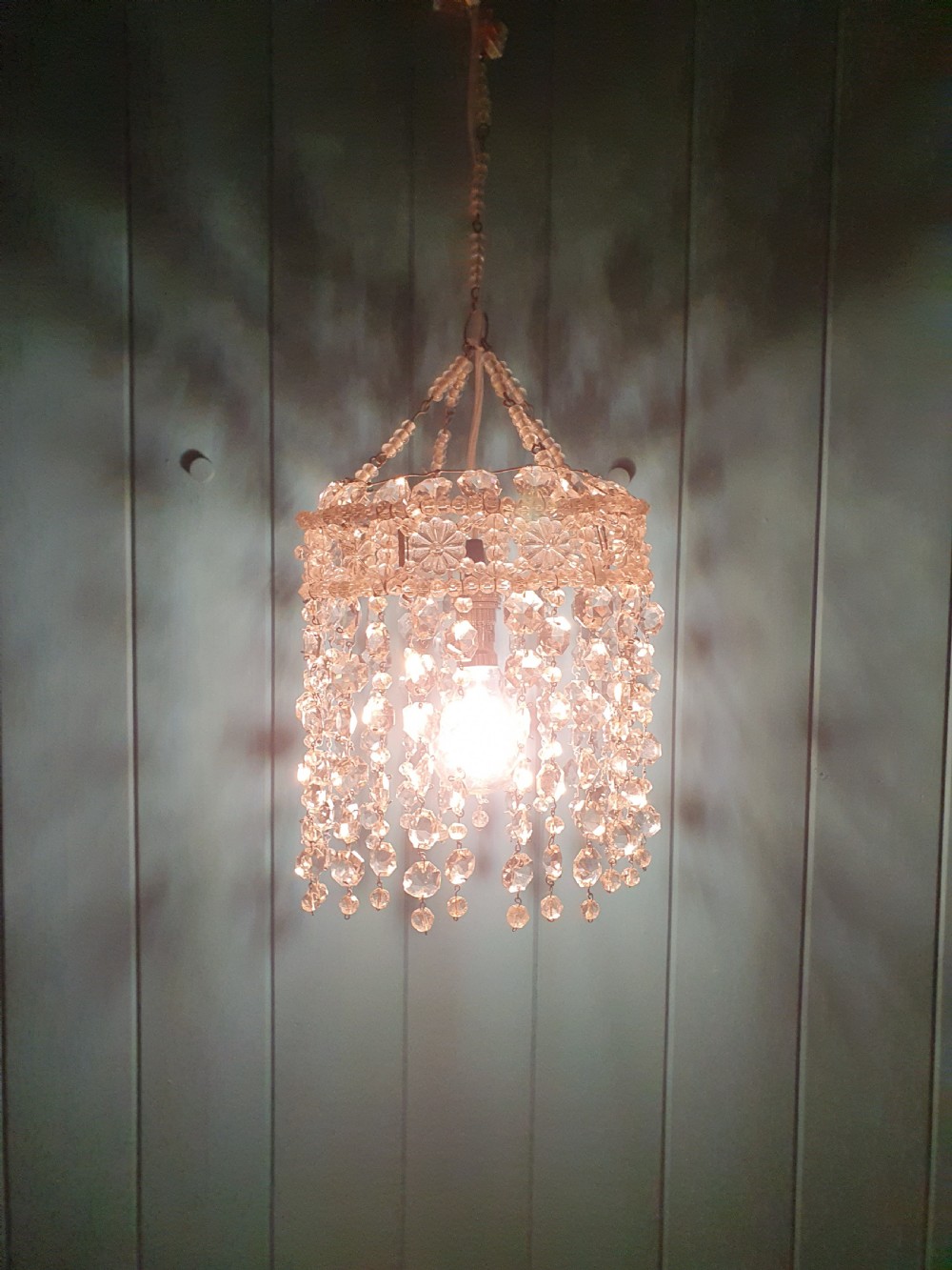 A small cylindrical ceiling light shade constructed from clear glass beads on a wire frame, featuring floral pattern bands and cascading faceted bead strands. View IV