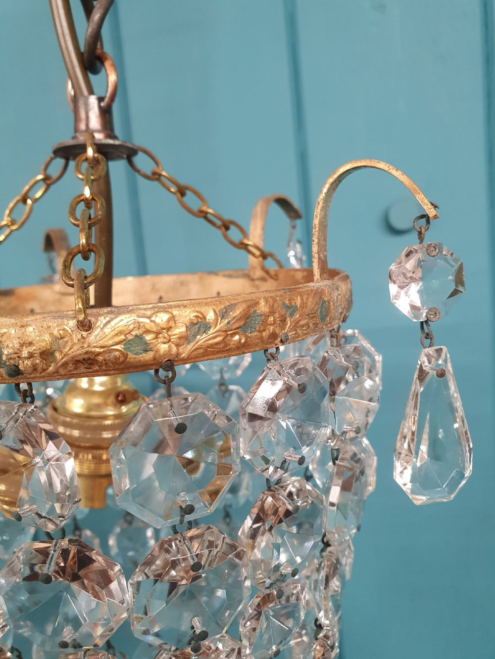 An early 20th-century small crystal bag chandelier featuring a brass filigree upper rim and faceted glass drops suspended from a brass chain. View VII