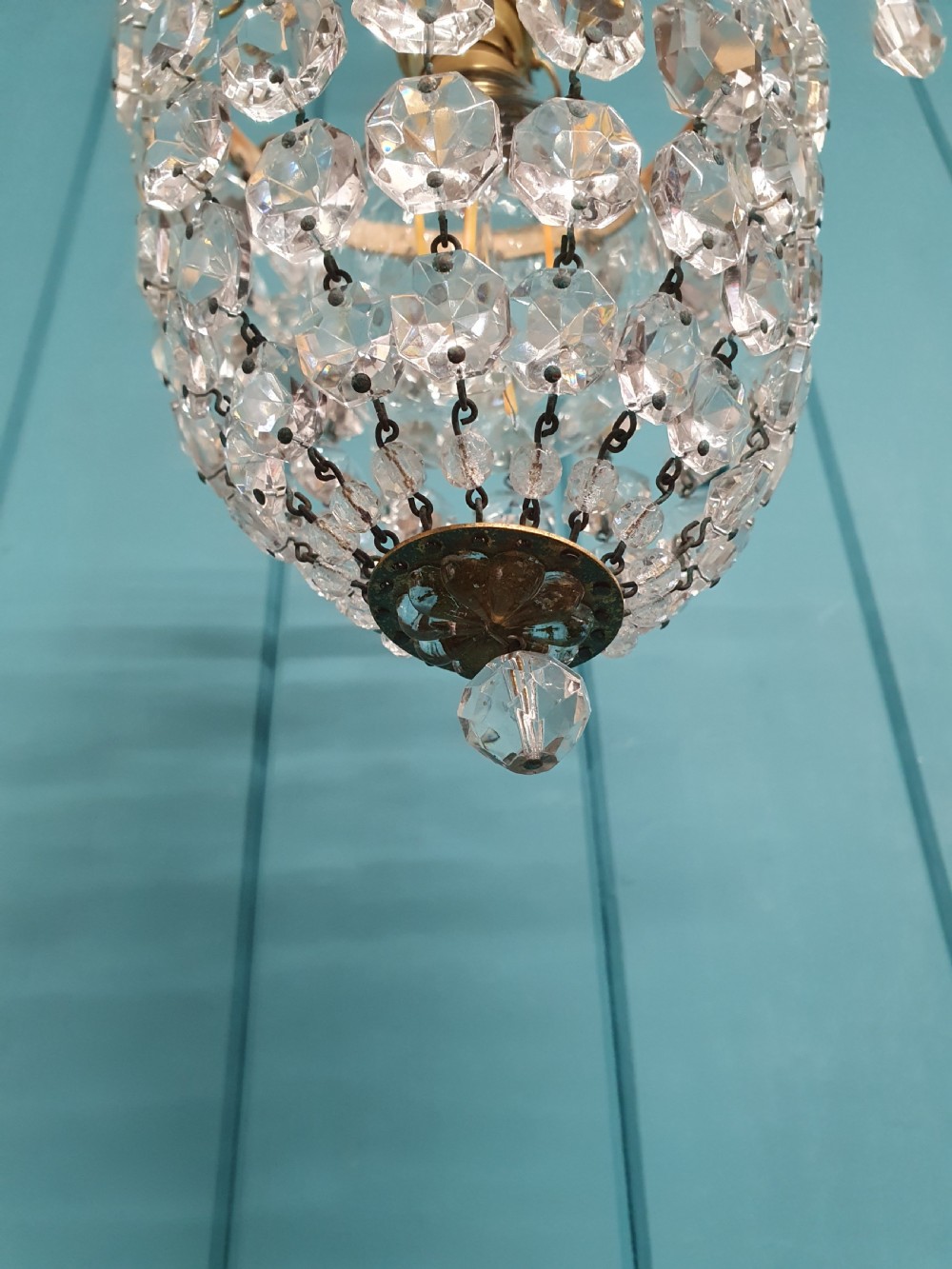 An early 20th-century small crystal bag chandelier featuring a brass filigree upper rim and faceted glass drops suspended from a brass chain. View IX