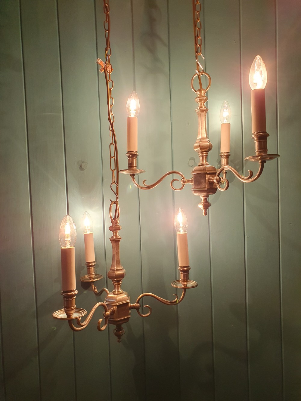 A pair of early twentieth-century nickel silver chandeliers, each featuring a central baluster stem, three scrolling arms, and candle-style lamp holders. View II