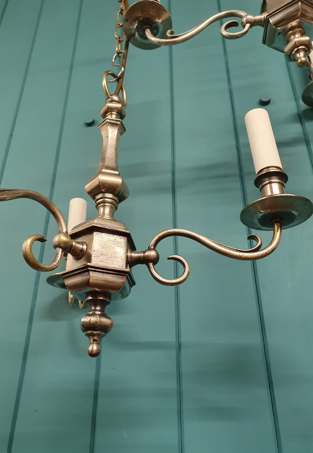 A pair of early twentieth-century nickel silver chandeliers, each featuring a central baluster stem, three scrolling arms, and candle-style lamp holders. View III