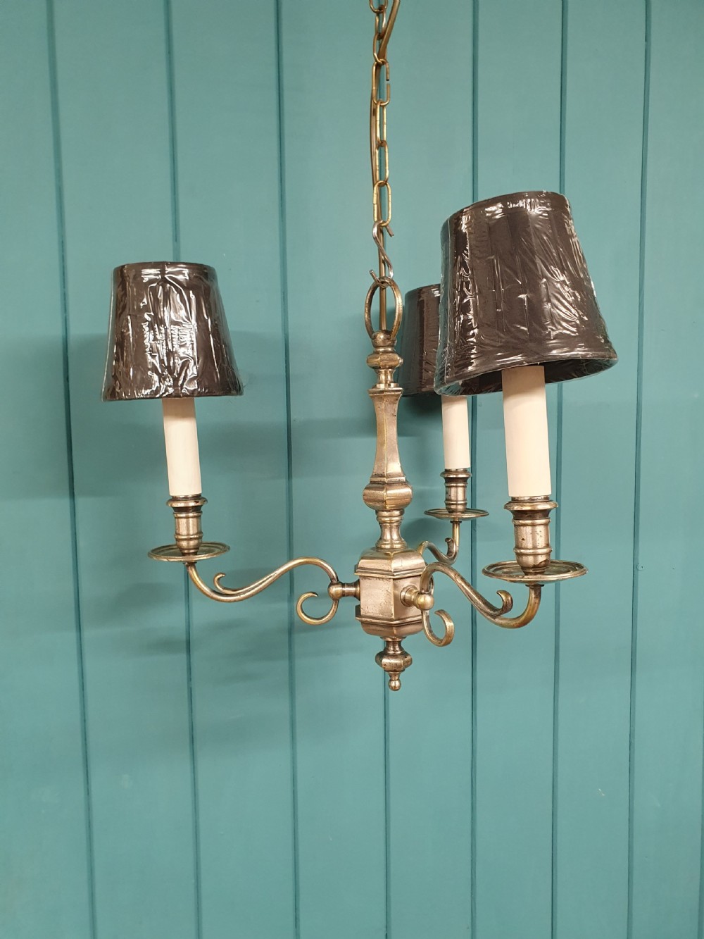 A pair of early twentieth-century nickel silver chandeliers, each featuring a central baluster stem, three scrolling arms, and candle-style lamp holders. View IV