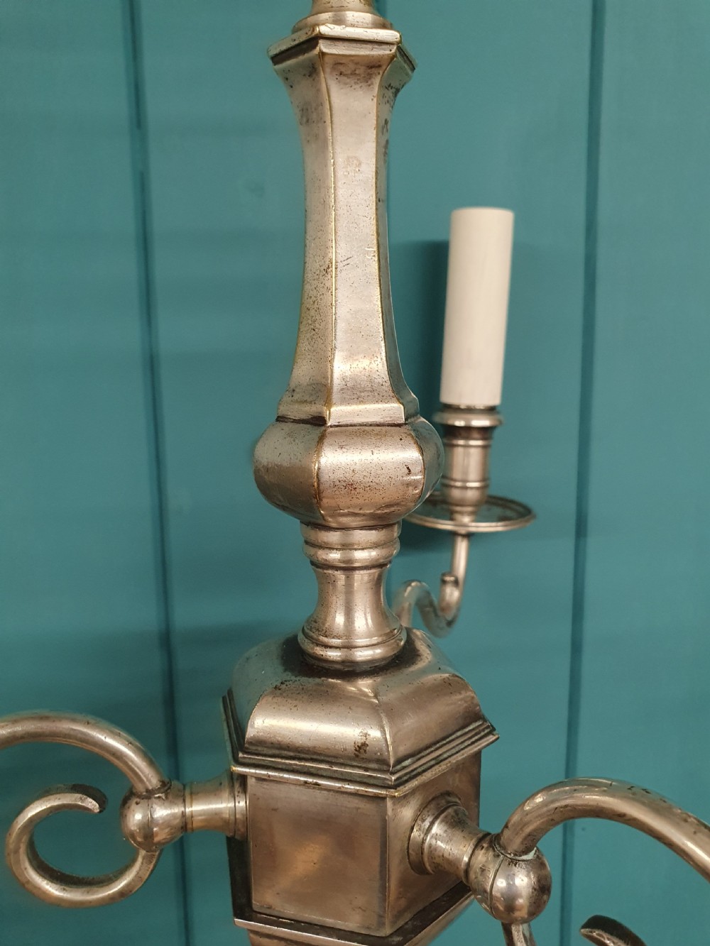 A pair of early twentieth-century nickel silver chandeliers, each featuring a central baluster stem, three scrolling arms, and candle-style lamp holders. View V