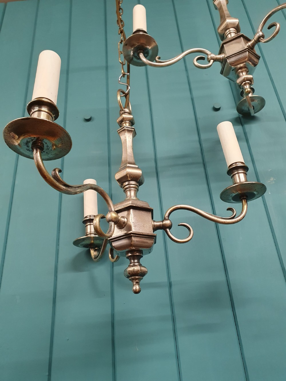 A pair of early twentieth-century nickel silver chandeliers, each featuring a central baluster stem, three scrolling arms, and candle-style lamp holders. View VII