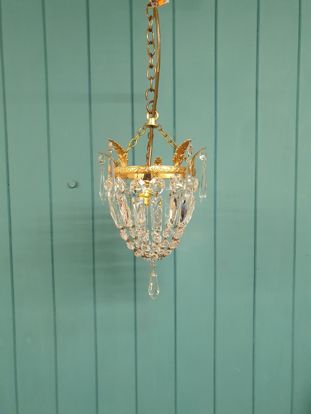 An eight-inch antique pouch-style chandelier featuring a decorative brass rim, cascading faceted glass prisms forming a basket shape, and a hanging crystal drop.