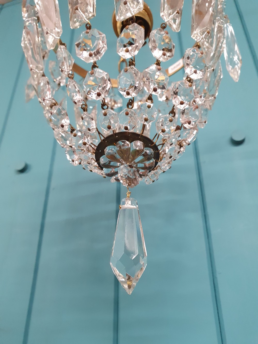 An eight-inch antique pouch-style chandelier featuring a decorative brass rim, cascading faceted glass prisms forming a basket shape, and a hanging crystal drop. View IV