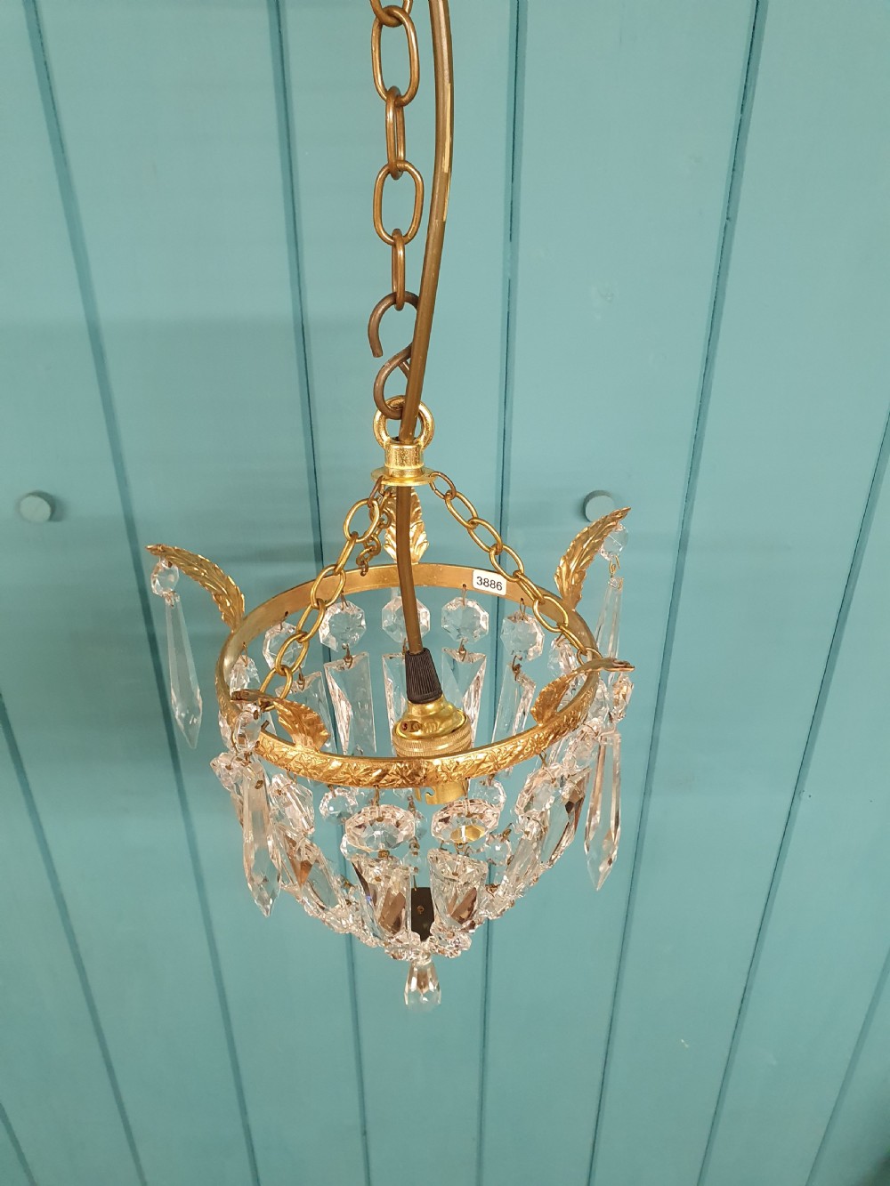 An eight-inch antique pouch-style chandelier featuring a decorative brass rim, cascading faceted glass prisms forming a basket shape, and a hanging crystal drop. View V