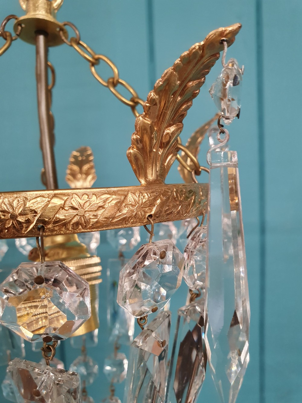 An eight-inch antique pouch-style chandelier featuring a decorative brass rim, cascading faceted glass prisms forming a basket shape, and a hanging crystal drop. View VI