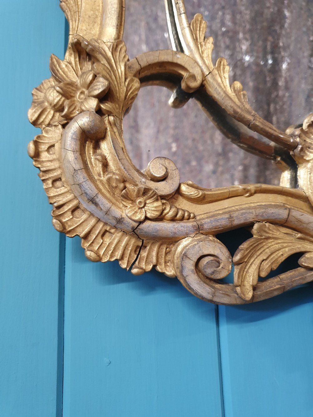 An ornate 19th-century Rococo style giltwood wall mirror featuring carved floral accents, scrollwork, and a decorative inner frame boundary. View II