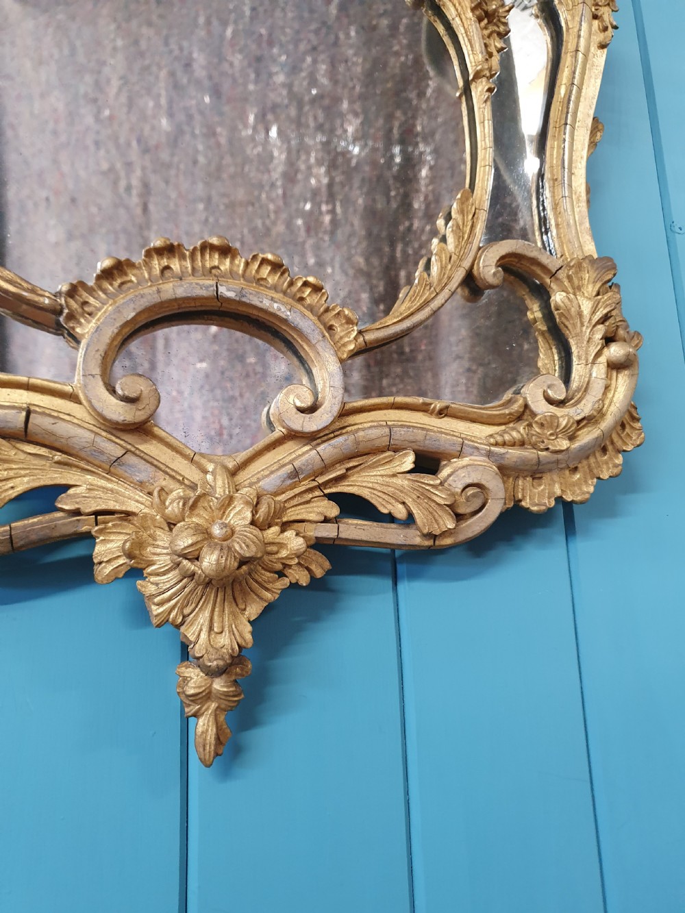 An ornate 19th-century Rococo style giltwood wall mirror featuring carved floral accents, scrollwork, and a decorative inner frame boundary. View IV