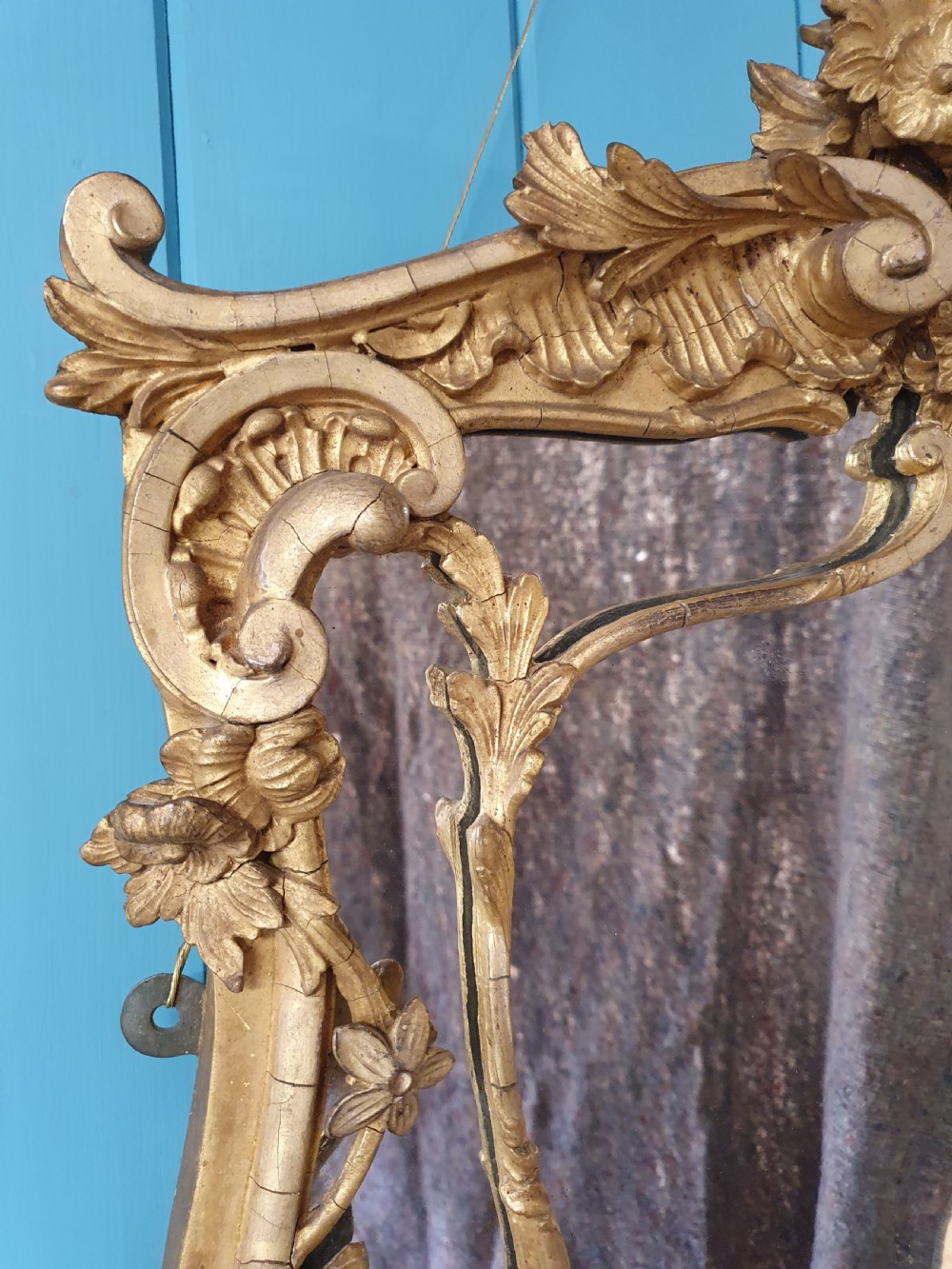 An ornate 19th-century Rococo style giltwood wall mirror featuring carved floral accents, scrollwork, and a decorative inner frame boundary. View VI