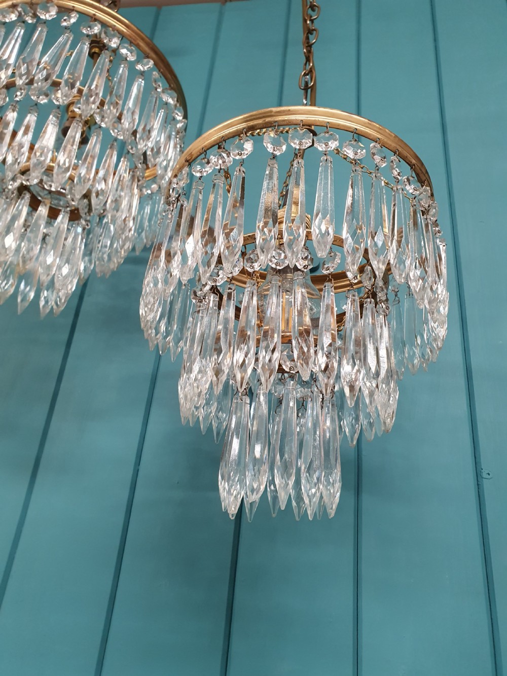 A pair of early 20th-century brass pendant chandeliers featuring tiered hanging crystal spikes suspended by linked chains. View III