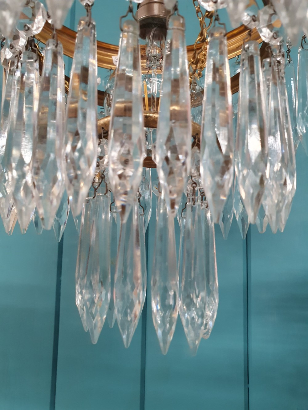 A pair of early 20th-century brass pendant chandeliers featuring tiered hanging crystal spikes suspended by linked chains. View V