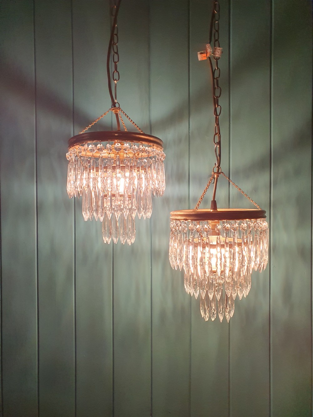 A pair of early 20th-century brass pendant chandeliers featuring tiered hanging crystal spikes suspended by linked chains. View VI