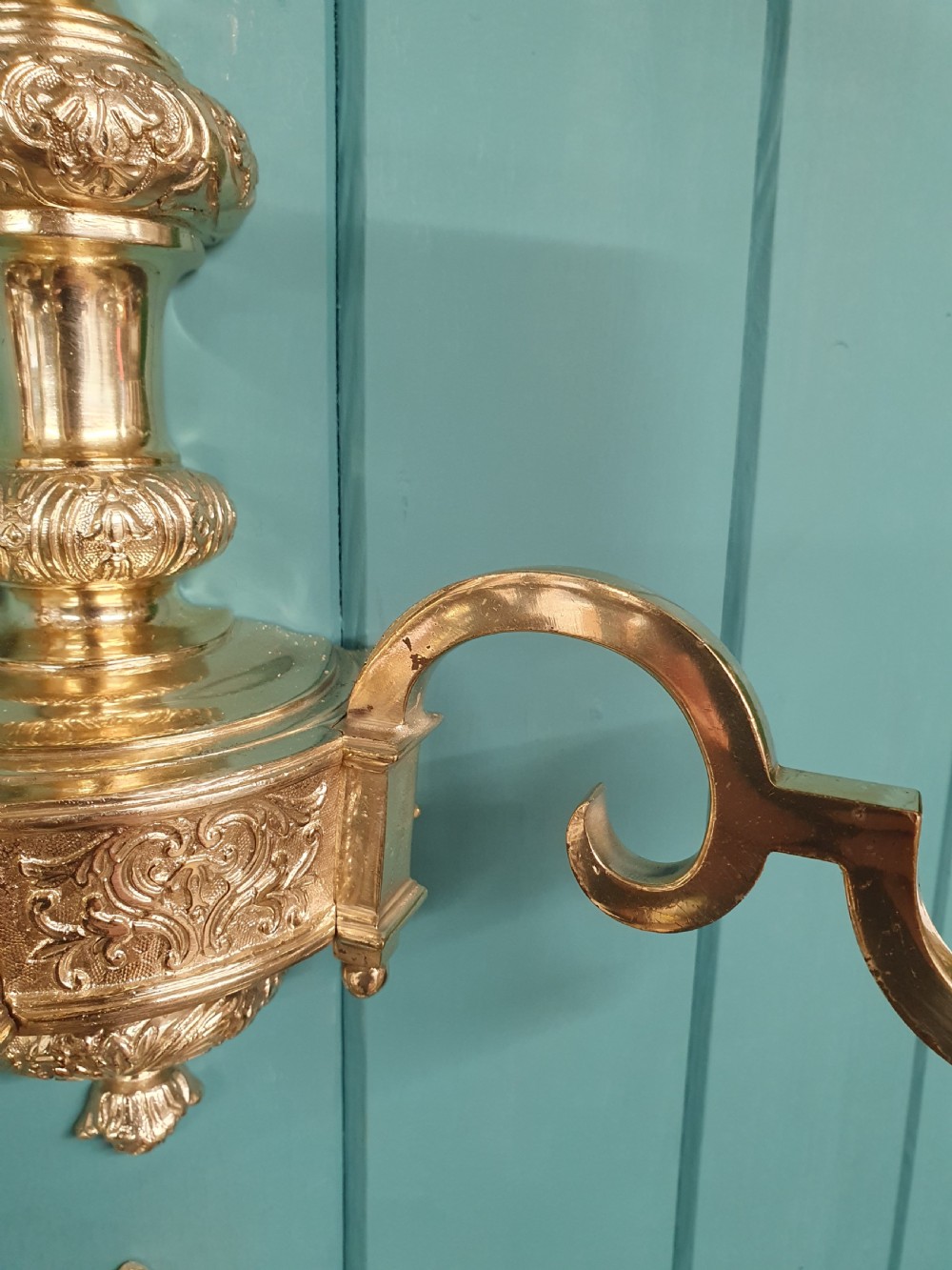 Set of seven silver-plated twin-branch wall lights featuring relief-carved backplates, urn finials, twin scroll arms, and faux candle sleeves. View II