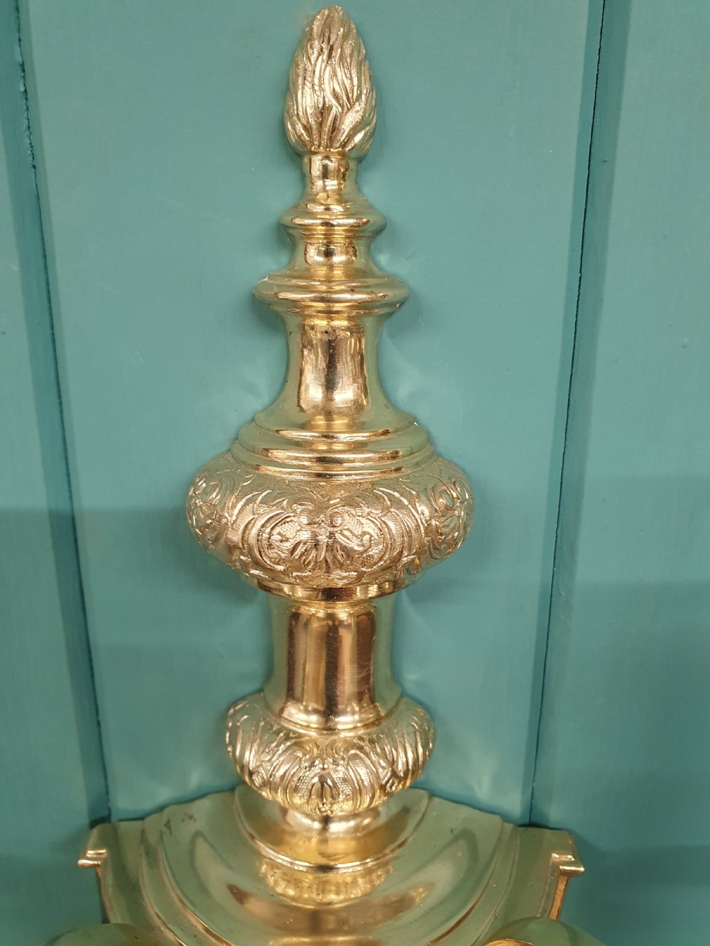 Set of seven silver-plated twin-branch wall lights featuring relief-carved backplates, urn finials, twin scroll arms, and faux candle sleeves. View V
