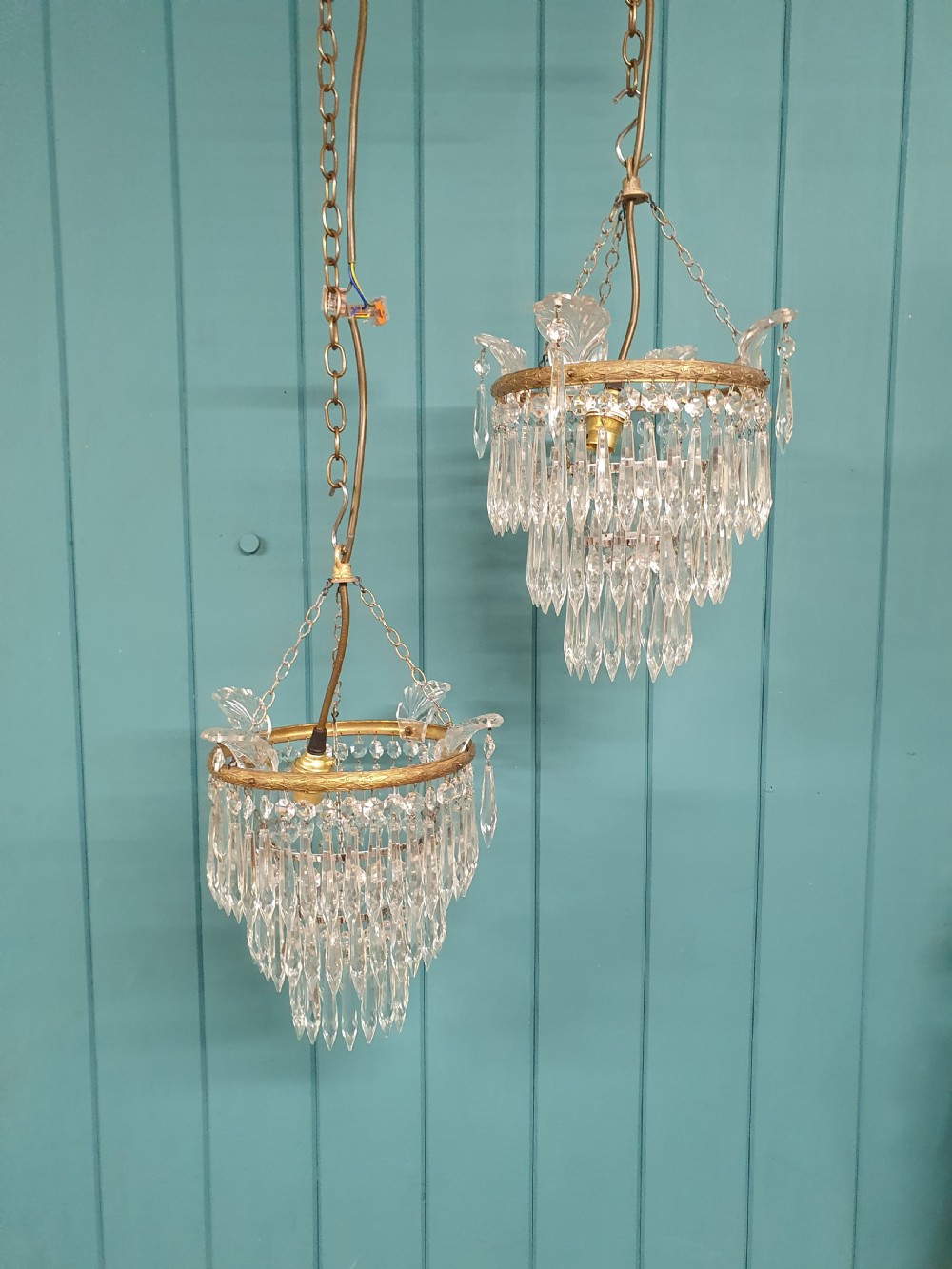 A pair of matching eleven-inch ceiling chandeliers featuring brass frames suspended with tiers of clear cut crystal glass spikes and drops.