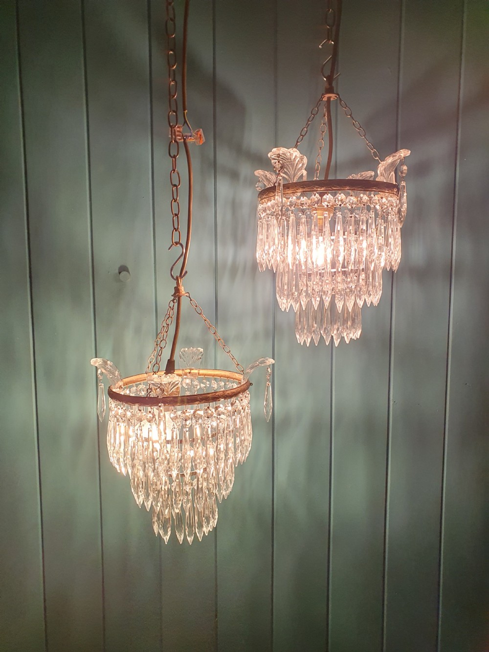 A pair of matching eleven-inch ceiling chandeliers featuring brass frames suspended with tiers of clear cut crystal glass spikes and drops. View II